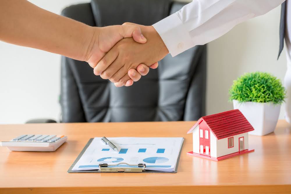 A realtor and a client shaking hands after closing a deal.