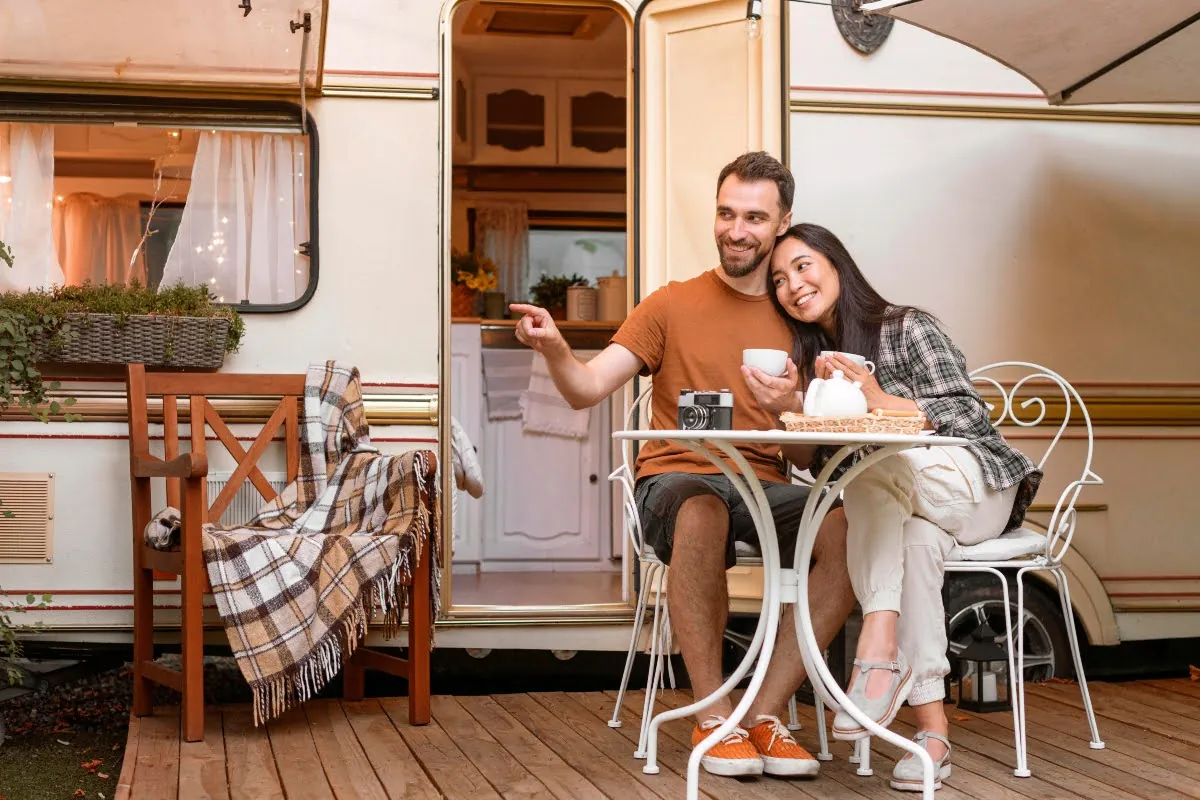 A couple sitting on the porch in front of their mobile home.